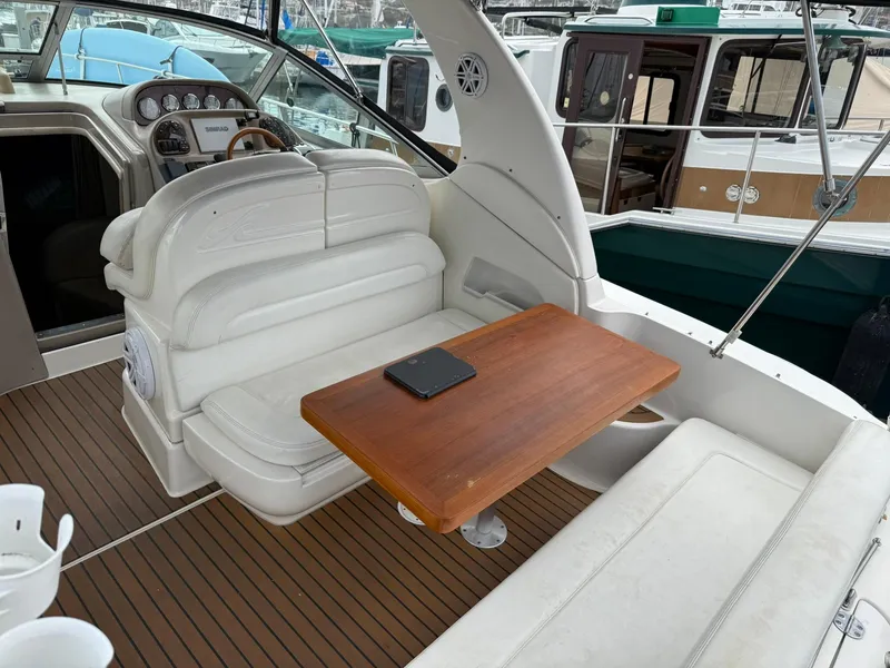 Slide: The Image of 2004 Sea Ray 300 Sundancer interior with white seating and wooden table. - 12