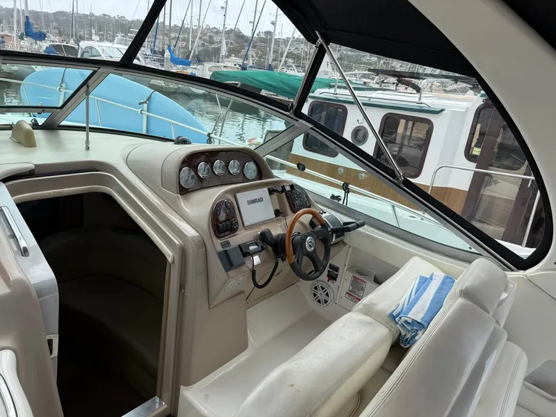 Slide: The Image of 2004 Sea Ray 300 Sundancer cockpit with steering wheel, gauges, and marina view. - 13