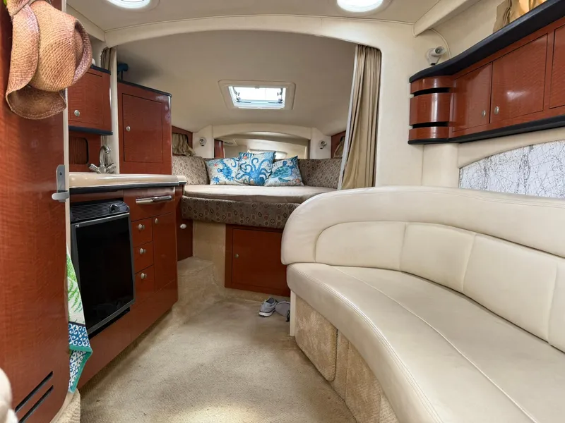 Slide: The Image of 2004 Sea Ray 300 Sundancer cabin interior with cozy seating and elegant wood cabinetry. - 3