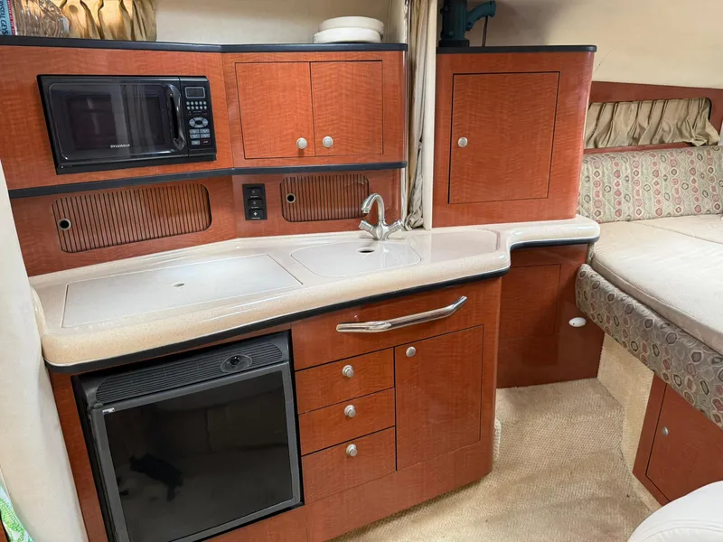 Slide: The Image of 2004 Sea Ray 300 Sundancer interior with kitchenette, featuring wood cabinetry and modern appliances. - 4