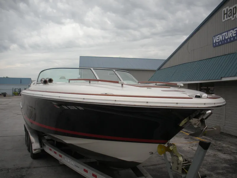 Slide: The Image of 2006 Chris-Craft Corsair 28 boat on trailer, parked outside under cloudy skies. - 4