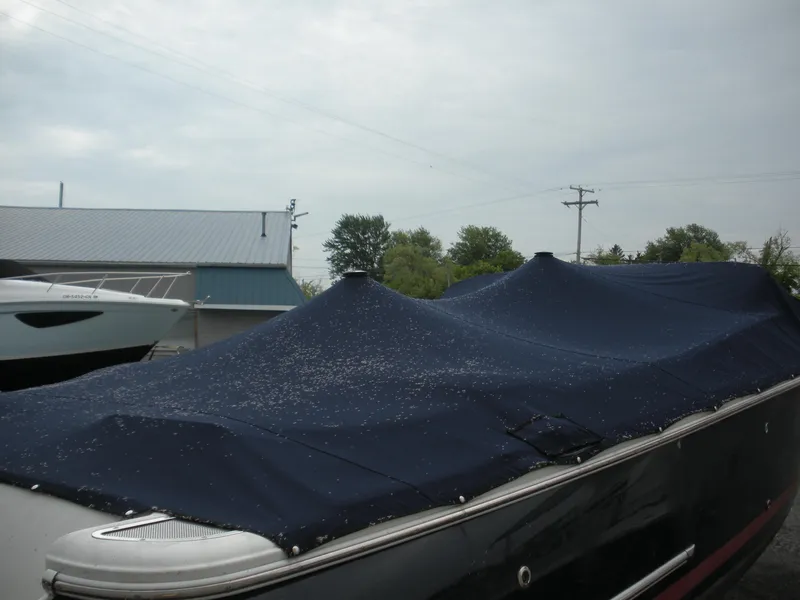 Slide: The Image of 2006 Chris-Craft Corsair 28 boat covered with a navy tarp, parked outdoors. - 8