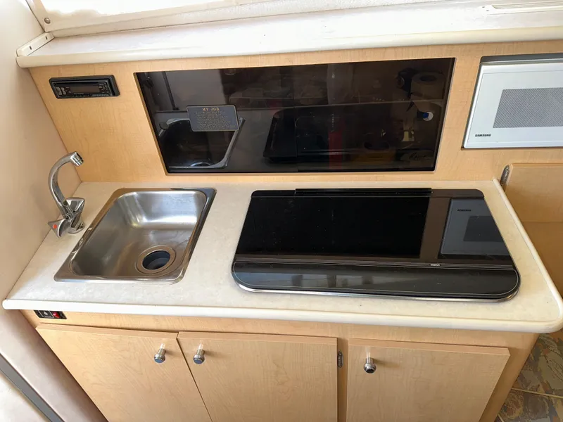 Slide: The Image of Compact kitchen area in a 2000 Bayliner 2855 Ciera boat, featuring a sink and stove. - 13