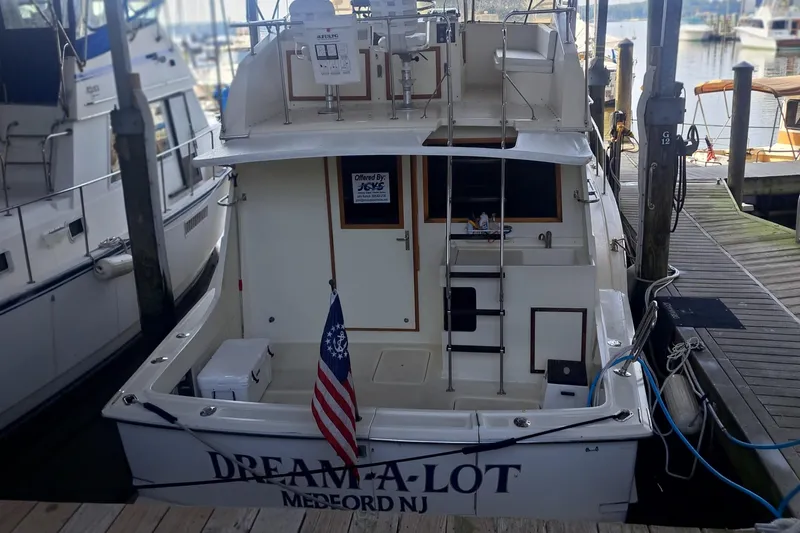 Slide: The Image of 1978 Hatteras 37 Convertible boat docked, rear view with American flag. - 7