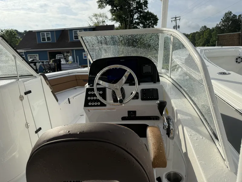 Slide: The Image of 2025 Sea Pro 240 DLX boat cockpit with steering wheel and controls, wet from rain. - 5