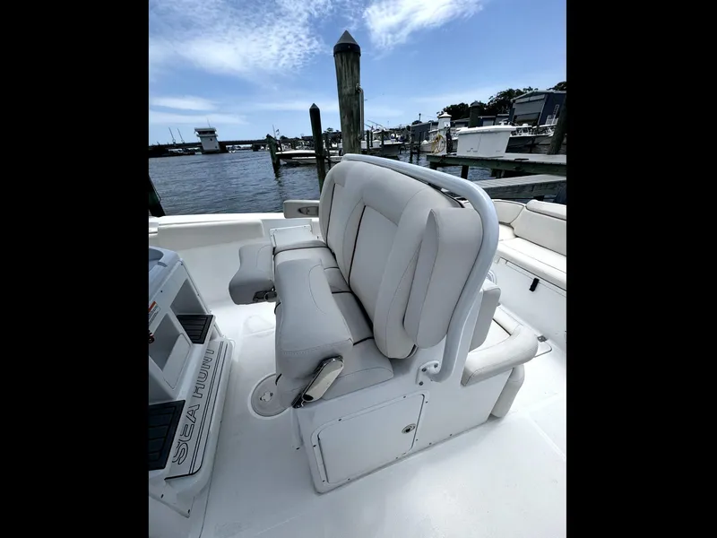 Slide: The Image of 2022 Sea Hunt Ultra 275 SE boat interior with cushioned seating at a marina. - 48