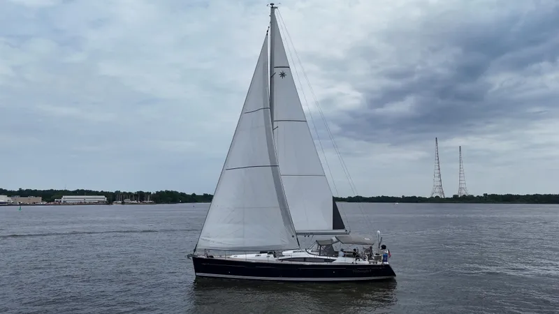Slide: The Image of 2016 Jeanneau Yachts 58 sailing on a calm river under a cloudy sky. - 22