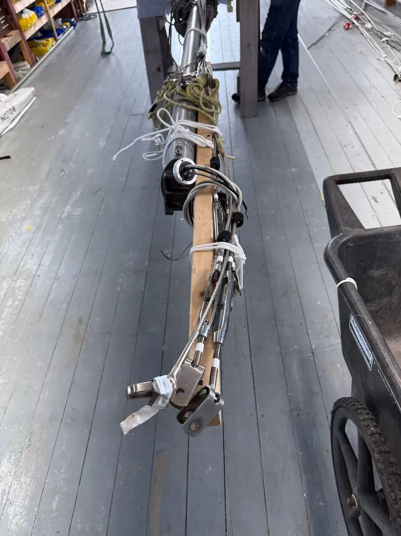 Slide: The Image of Mast of 2006 Mas Mini Transat 6.50 sailboat on wooden floor, with rigging and cart. - 14