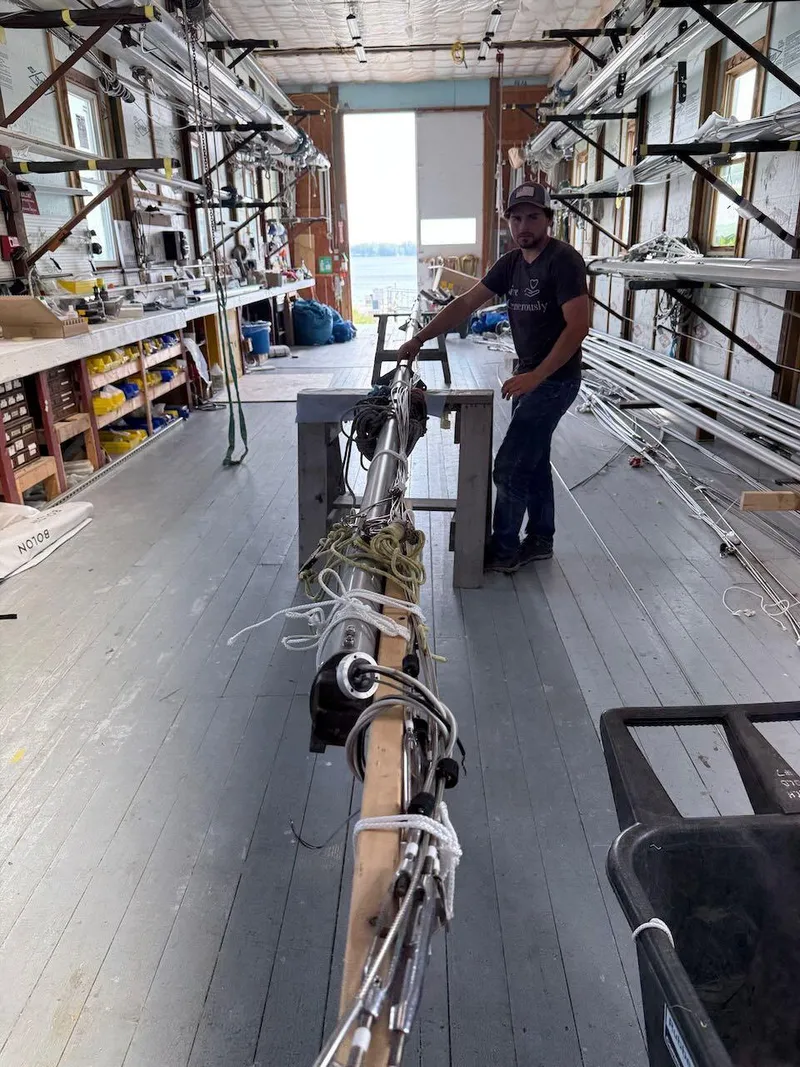 Slide: The Image of Man working on a 2006 Mas Mini Transat 6.50 mast in a workshop. - 15