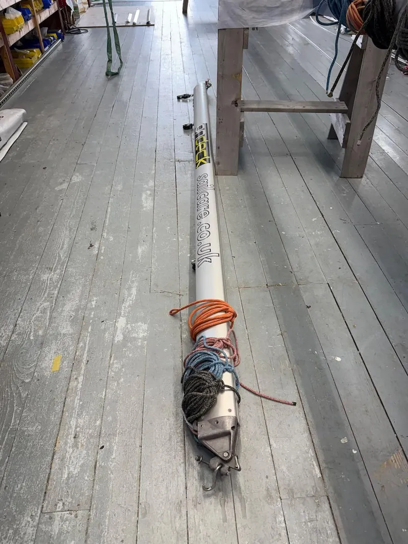 Slide: The Image of Mast of 2006 Mas Mini Transat 6.50 sailboat on wooden floor, coiled ropes attached. - 20