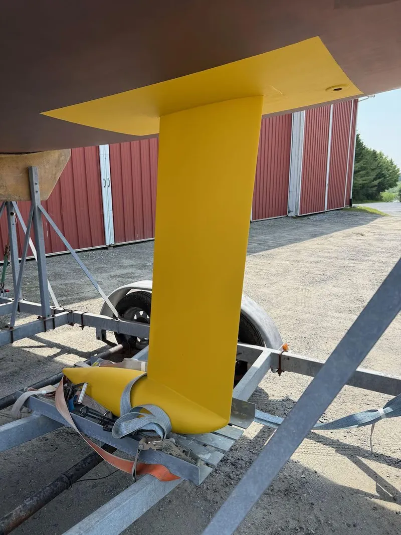 Slide: The Image of Yellow keel of 2006 Mas Mini Transat 6.50 sailboat on trailer. - 3