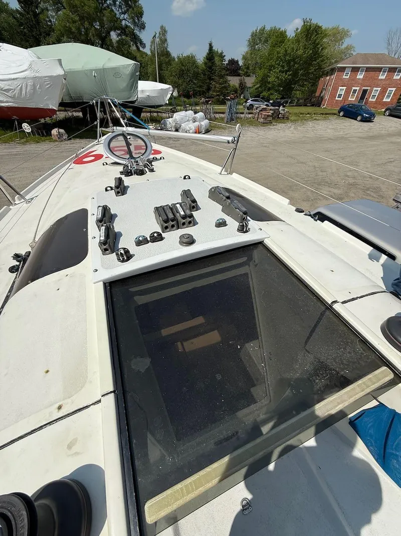 Slide: The Image of 2006 Mas Mini Transat 6.50 sailboat deck with equipment, parked outdoors. - 34