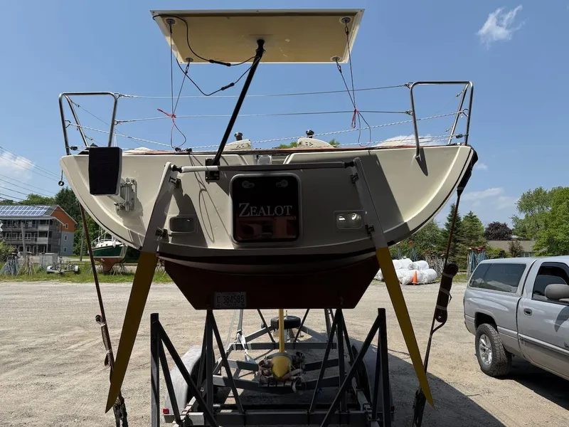 Slide: The Image of 2006 Mas Mini Transat 6.50 sailboat on trailer, parked outdoors under clear sky. - 5