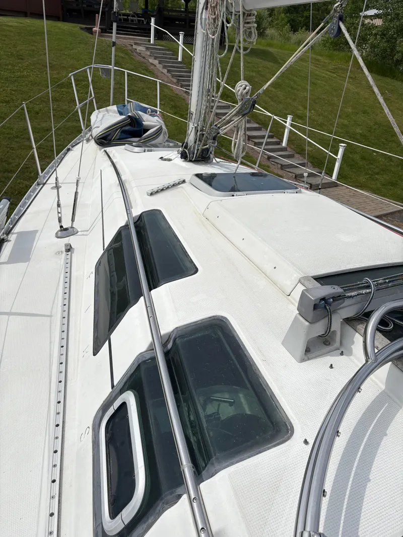 Slide: The Image of 1989 Beneteau 32s5 sailboat deck with rigging and windows, docked near grassy area. - 18