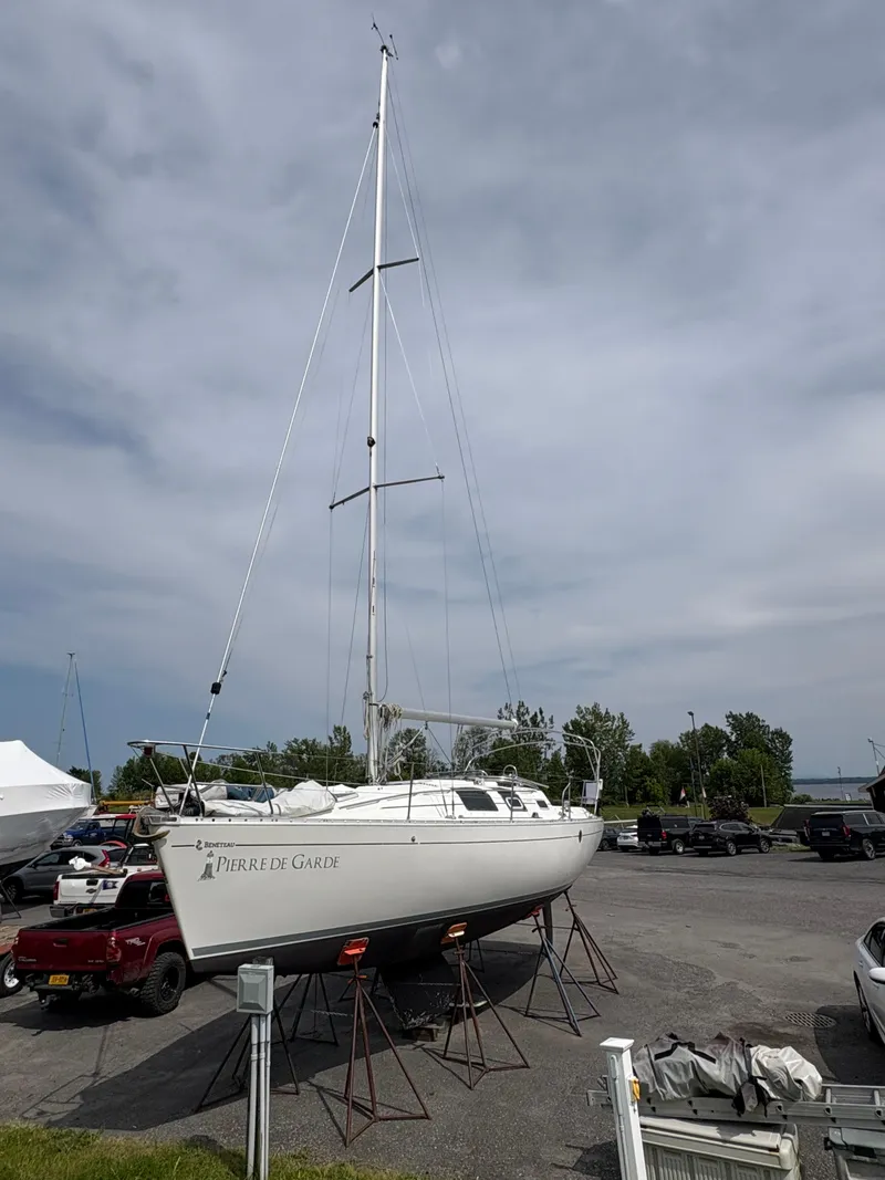 Slide: The Image of 1989 Beneteau 32s5 sailboat on stands in a parking lot under a cloudy sky. - 2