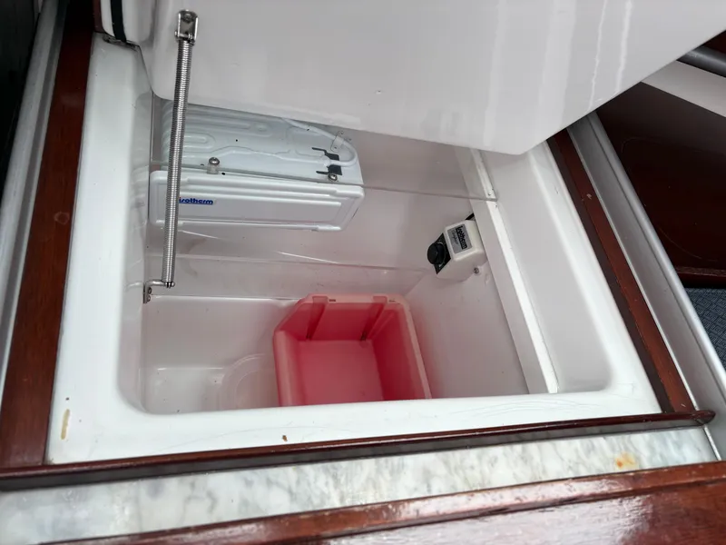 Slide: The Image of Open storage compartment in 1989 Beneteau 32s5 yacht with red container inside. - 26