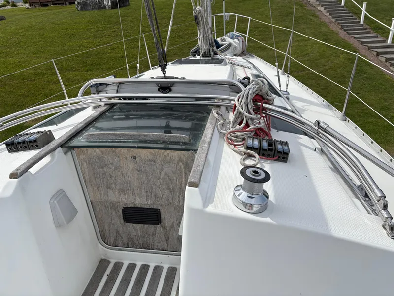 Slide: The Image of 1989 Beneteau 32s5 sailboat deck with ropes and winch, docked on grassy shore. - 20