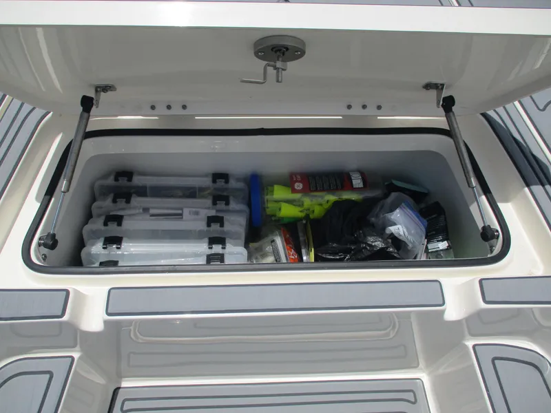 Slide: The Image of Open storage compartment on 2023 Skeeter SX 240 boat, filled with fishing gear and supplies. - 15