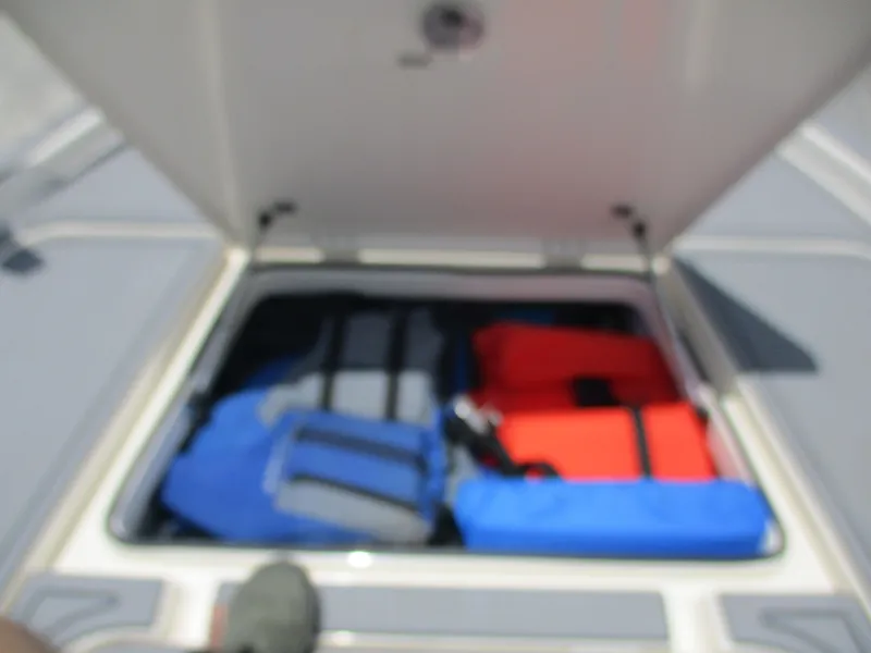 Slide: The Image of Open storage compartment on 2023 Skeeter SX 240 boat with life jackets inside. - 16
