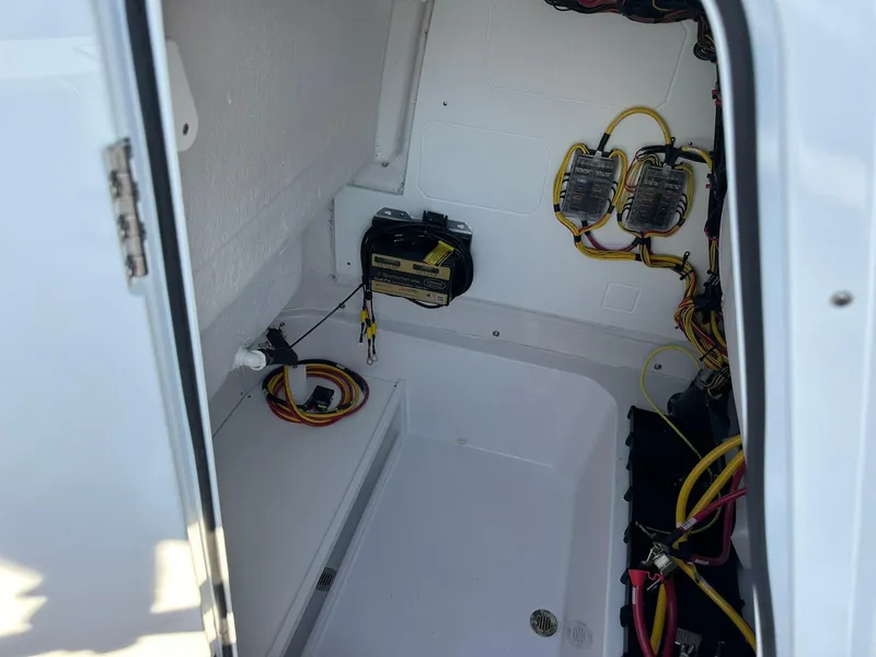 Slide: The Image of Electrical compartment of 2025 Sportsman Open 232 Center Console boat, showing wiring and battery. - 24