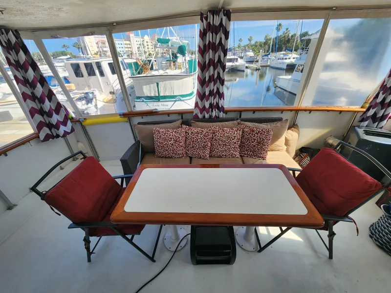Slide: The Image of 1979 Hatteras 58 Long Range Cruiser interior with cozy seating and marina view. - 17