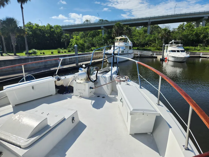 Slide: The Image of 1979 Hatteras 58 Long Range Cruiser docked at a marina under a sunny sky. - 23