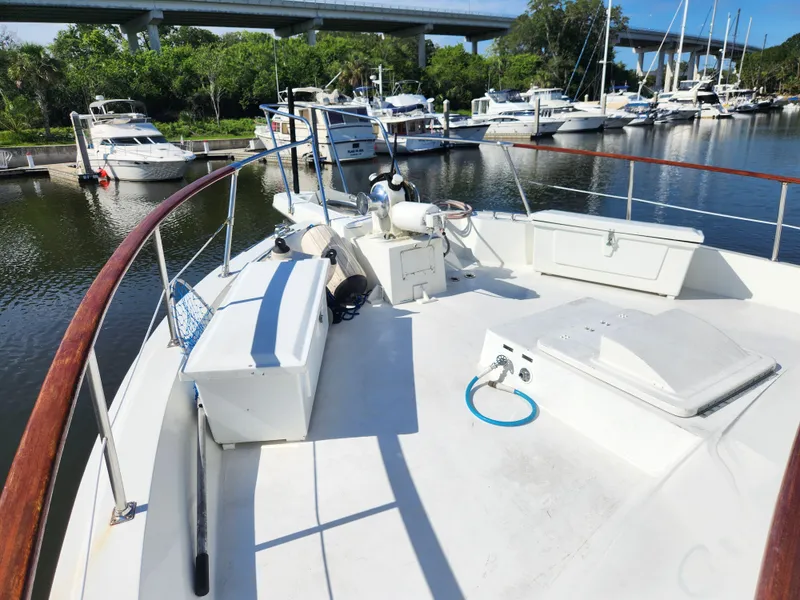 Slide: The Image of 1979 Hatteras 58 Long Range Cruiser docked at marina, featuring spacious deck and railing. - 24
