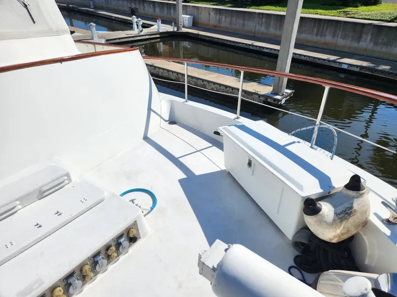 Slide: The Image of 1979 Hatteras 58 Long Range Cruiser deck with storage and railing, docked by calm water. - 26
