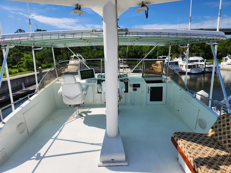 Slide: The Image of 1979 Hatteras 58 Long Range Cruiser helm with seating, docked in a marina under clear skies. - 30