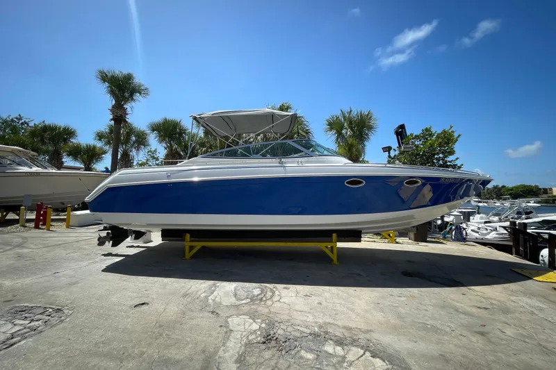 Slide: The Image of 2000 Formula 330 SS boat on display, blue hull, sunny day, palm trees in background. - 8