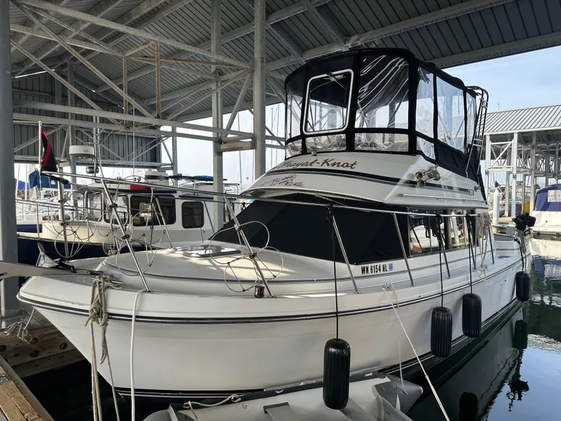 The Image of 1988 Carver 280 Voyager docked in a marina under a metal roof. - 1