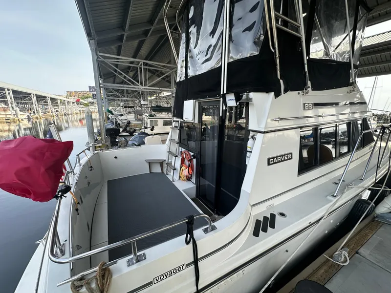 Slide: The Image of 1988 Carver 280 Voyager docked at marina, featuring spacious deck and covered upper helm. - 3