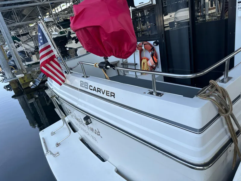 Slide: The Image of 1988 Carver 280 Voyager docked, displaying American flag and safety equipment. - 4