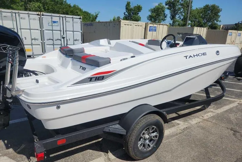 The Image of 2025 Tahoe T18 boat on trailer, white with red accents, parked outdoors. - 0