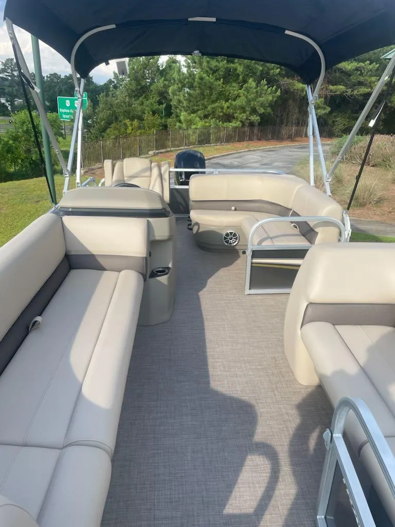 Slide: The Image of 2025 Sun Tracker Party Barge 18 DLX with spacious seating and canopy, parked outdoors. - 3