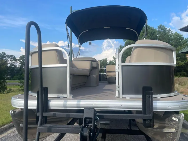Slide: The Image of 2025 Sun Tracker Party Barge 18 DLX pontoon boat with canopy, parked outdoors. - 4