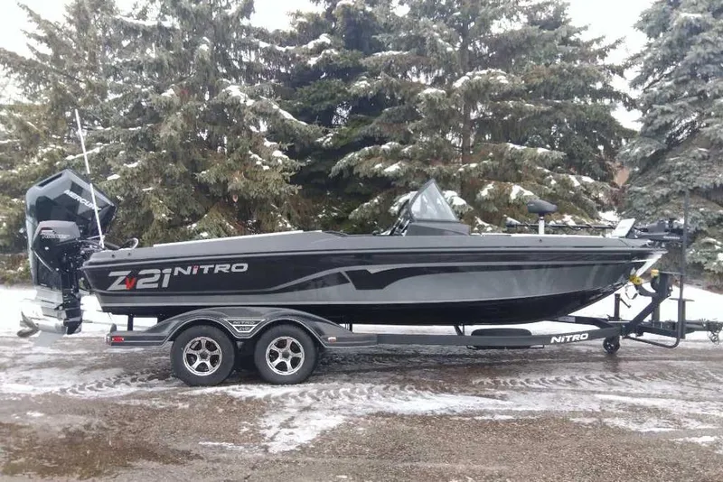 The Image of 2025 Nitro ZV21 Pro boat on trailer, parked in snowy landscape with trees. - 0