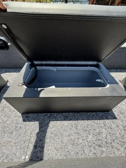 Slide: The Image of Open storage compartment in 2025 Tracker Panfish 17 boat, featuring gray interior and carpeted flooring. - 6