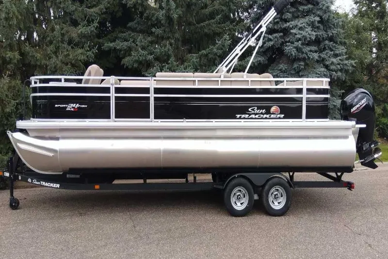Slide: The Image of 2025 Sun Tracker Sportfish 24 XP3 pontoon boat on trailer, parked outdoors. - 7