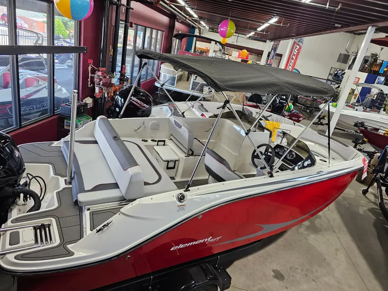 Slide: The Image of 2023 Bayliner Element M19 boat with canopy in showroom, featuring red and white design. - 4