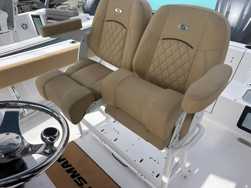Slide: The Image of 2025 Sportsman Heritage 231 Center Console boat seats with tan upholstery and steering wheel. - 27