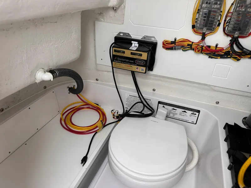 Slide: The Image of 2025 Sportsman Heritage 231 Center Console boat interior with wiring and marine toilet. - 43