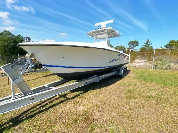 Slide: The Image of 1999 Contender 28 Sport boat on trailer, parked on grass under blue sky. - 13