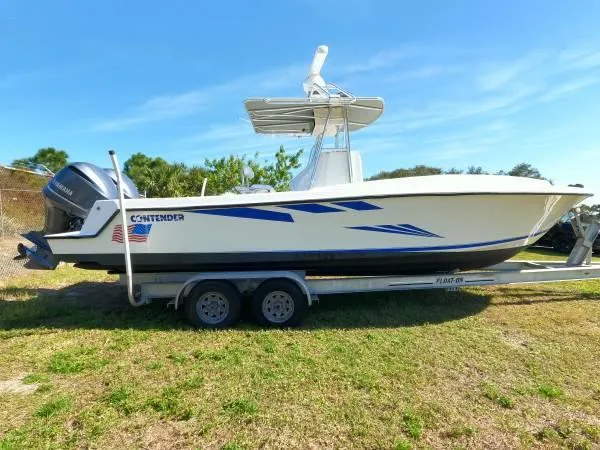Slide: The Image of 1999 Contender 28 Sport boat on trailer, side view, outdoors under clear blue sky. - 14