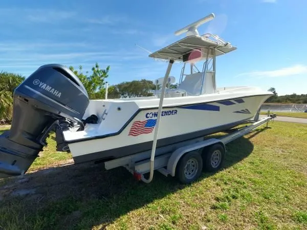 Slide: The Image of 1999 Contender 28 Sport boat on trailer with Yamaha outboard, parked on grass. - 15