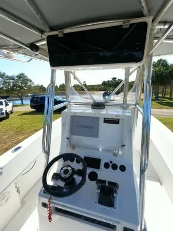 Slide: The Image of 1999 Contender 28 Sport boat console with steering wheel and controls, parked near a lake. - 3