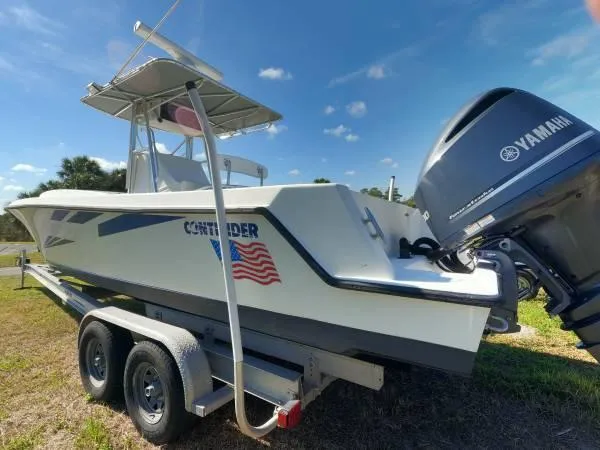 Slide: The Image of 1999 Contender 28 Sport boat on trailer with Yamaha engine, parked on grass under blue sky. - 5