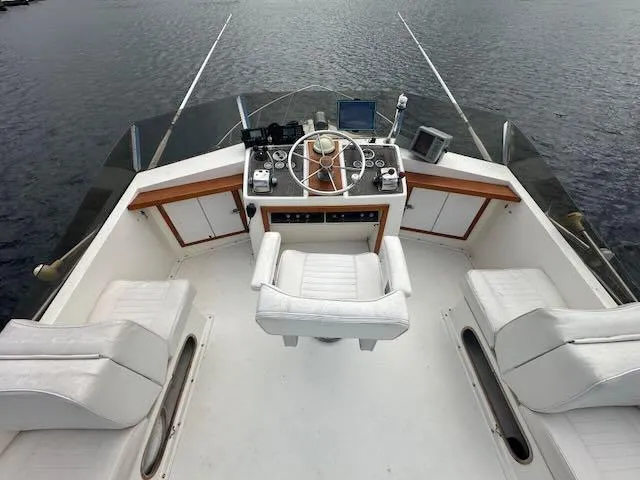 Slide: The Image of 1978 Egg Harbor 36 Sedan boat helm with white seating and control panel on water. - 33