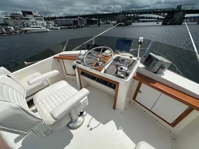 Slide: The Image of 1978 Egg Harbor 36 Sedan boat helm with white seating, steering wheel, and control panel on a sunny day. - 35