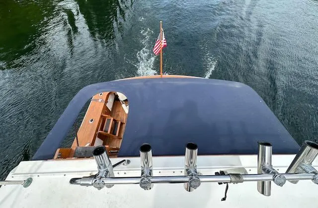Slide: The Image of 1978 Egg Harbor 36 Sedan boat with fishing rod holders and American flag on water. - 41